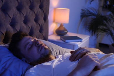 Handsome man sleeping on pillow in dark room at night. Bedtime