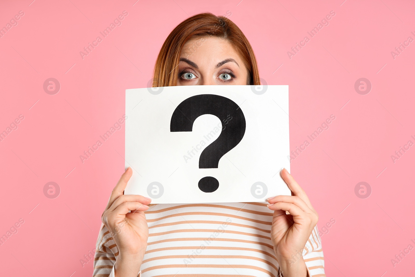 Photo of Emotional woman holding question mark sign on pink background