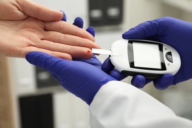 Diabetes. Doctor checking patient's blood sugar level with glucometer in clinic, closeup