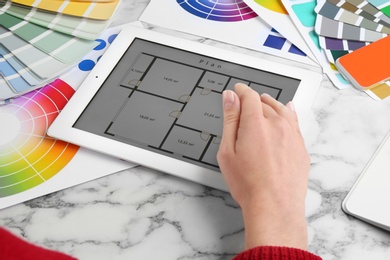 Photo of Woman working with tablet and palette samples at white marble table, closeup