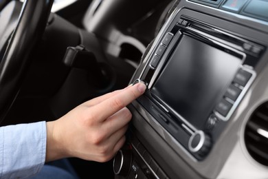 Photo of Listening to radio while driving. Woman turning volume button on vehicle audio in car, closeup