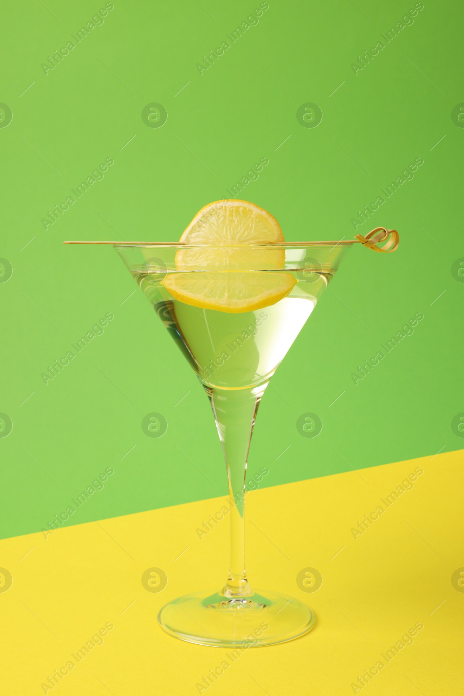 Photo of Martini glass of refreshing cocktail with lemon slice on color background
