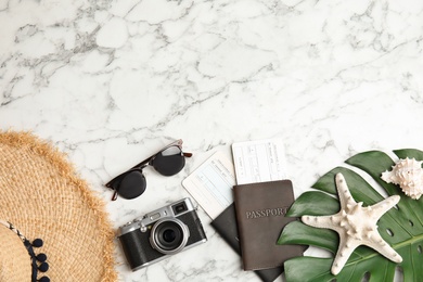 Flat lay composition with tourist items and camera on marble background, space for text. Travel agency