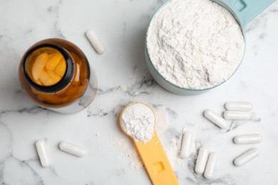 Photo of Amino acid pills and powder on white marble table, flat lay