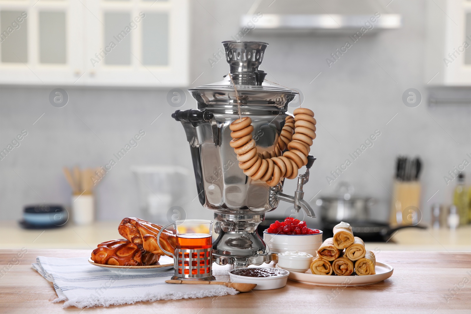 Image of Traditional Russian samovar and treats on wooden table in kitchen