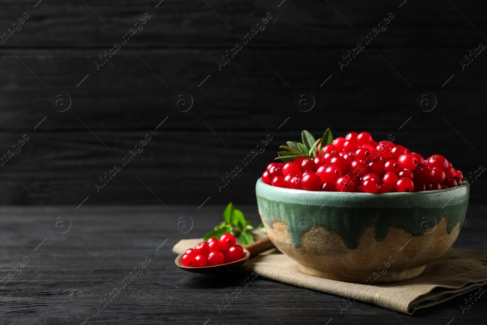 Photo of Tasty ripe cranberries on black wooden table. Space for text