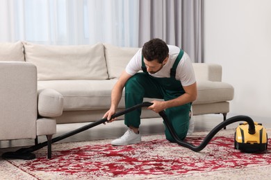 Photo of Dry cleaner's employee hoovering carpet with vacuum cleaner in room