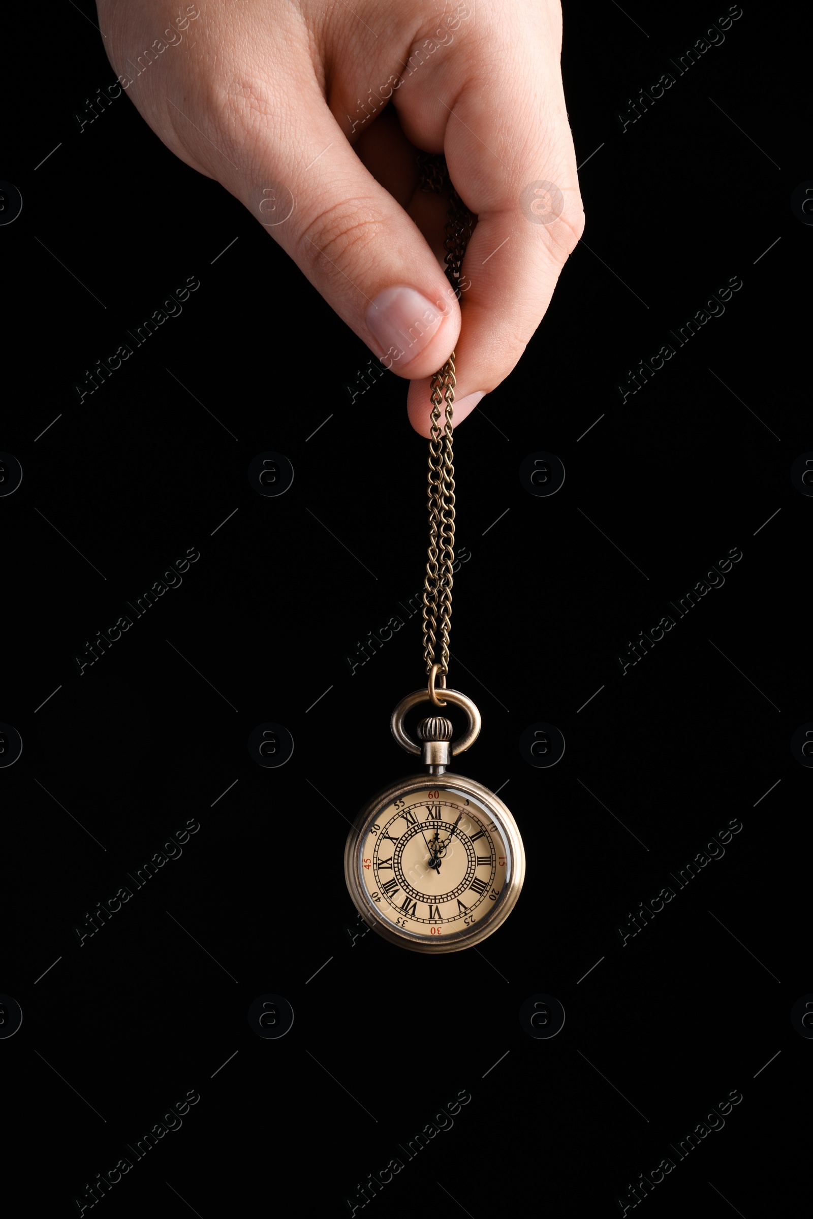 Photo of Psychotherapist with pendulum on black background, closeup. Hypnotherapy session