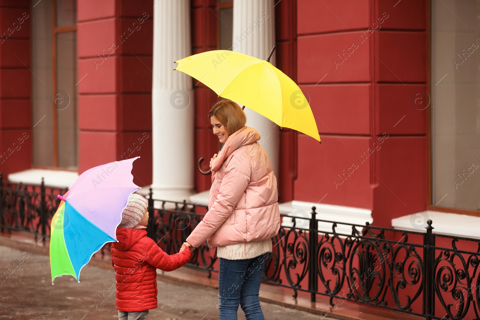 Photo of Mother and daughter with umbrellas in city on autumn rainy day