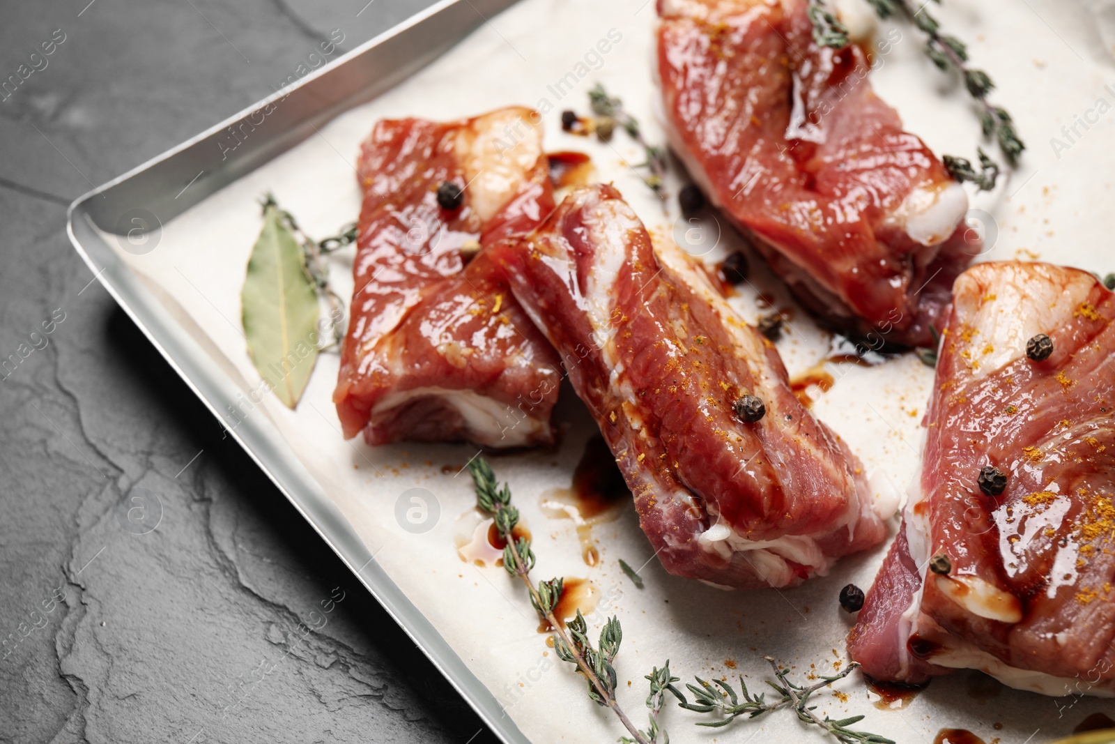 Photo of Raw marinated ribs on black table, closeup