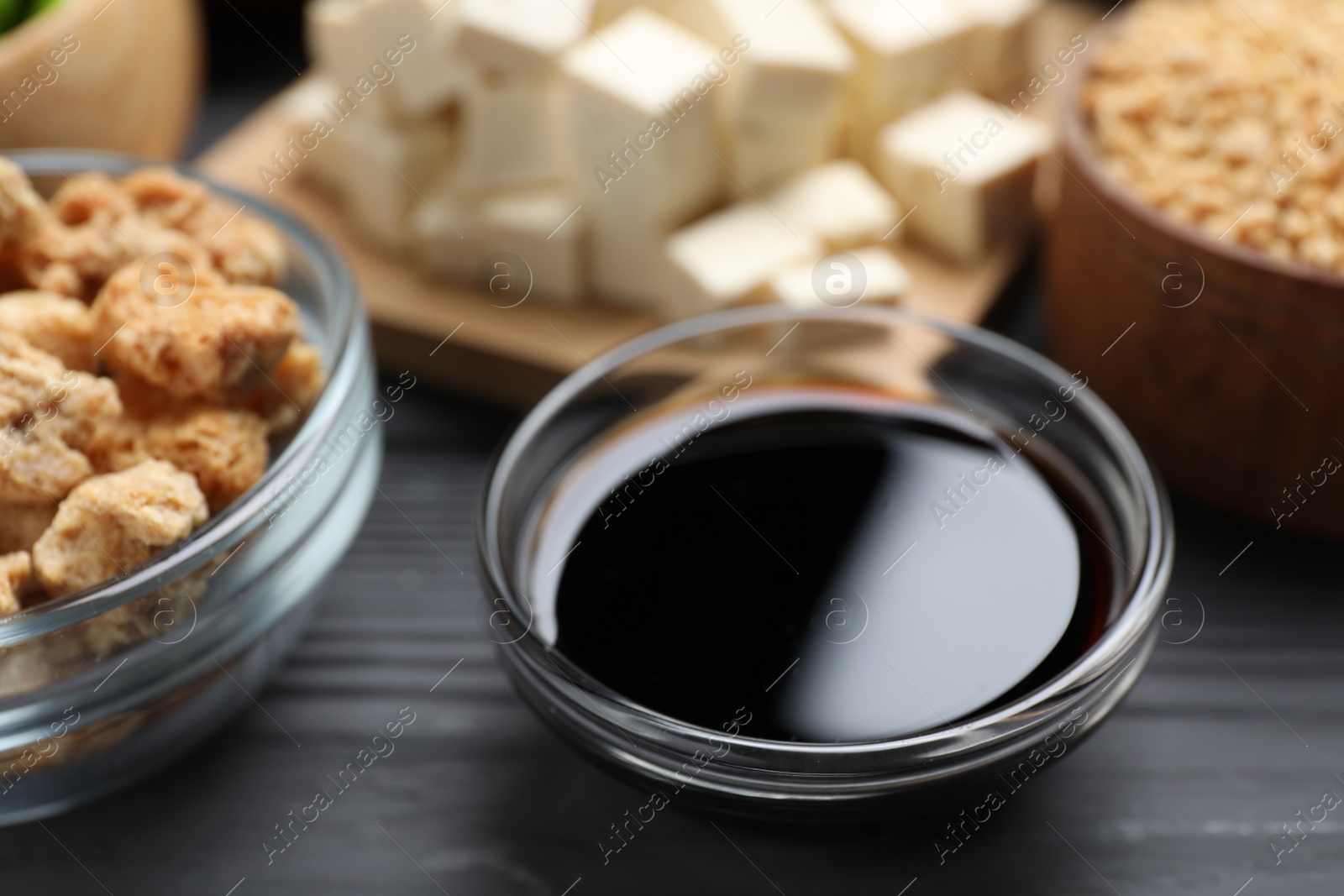 Photo of Soy sauce and other organic products on grey wooden table, closeup