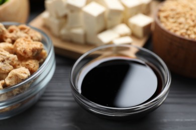 Soy sauce and other organic products on grey wooden table, closeup