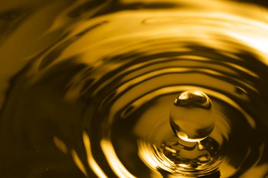 Splash of golden oily liquid with drop as background, closeup