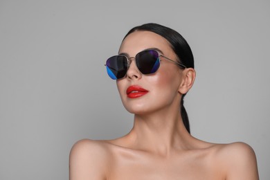 Photo of Attractive woman in fashionable sunglasses against grey background. Space for text