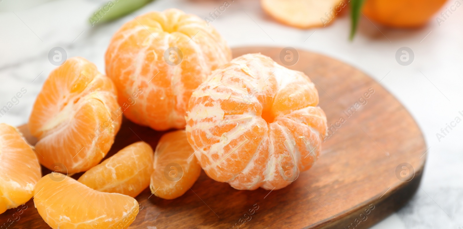 Photo of Fresh peeled tangerines on wooden board, closeup