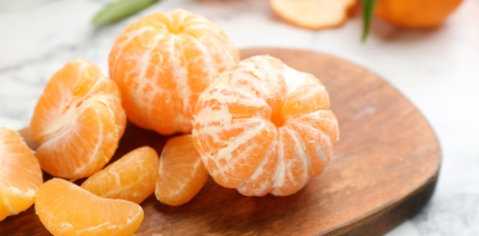 Photo of Fresh peeled tangerines on wooden board, closeup