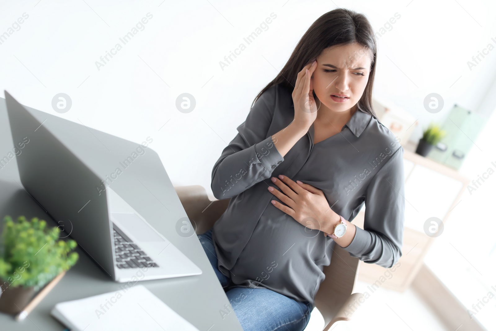 Photo of Pregnant woman suffering from headache at workplace