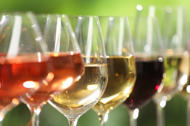 Photo of Different tasty wines in glasses against blurred background, closeup