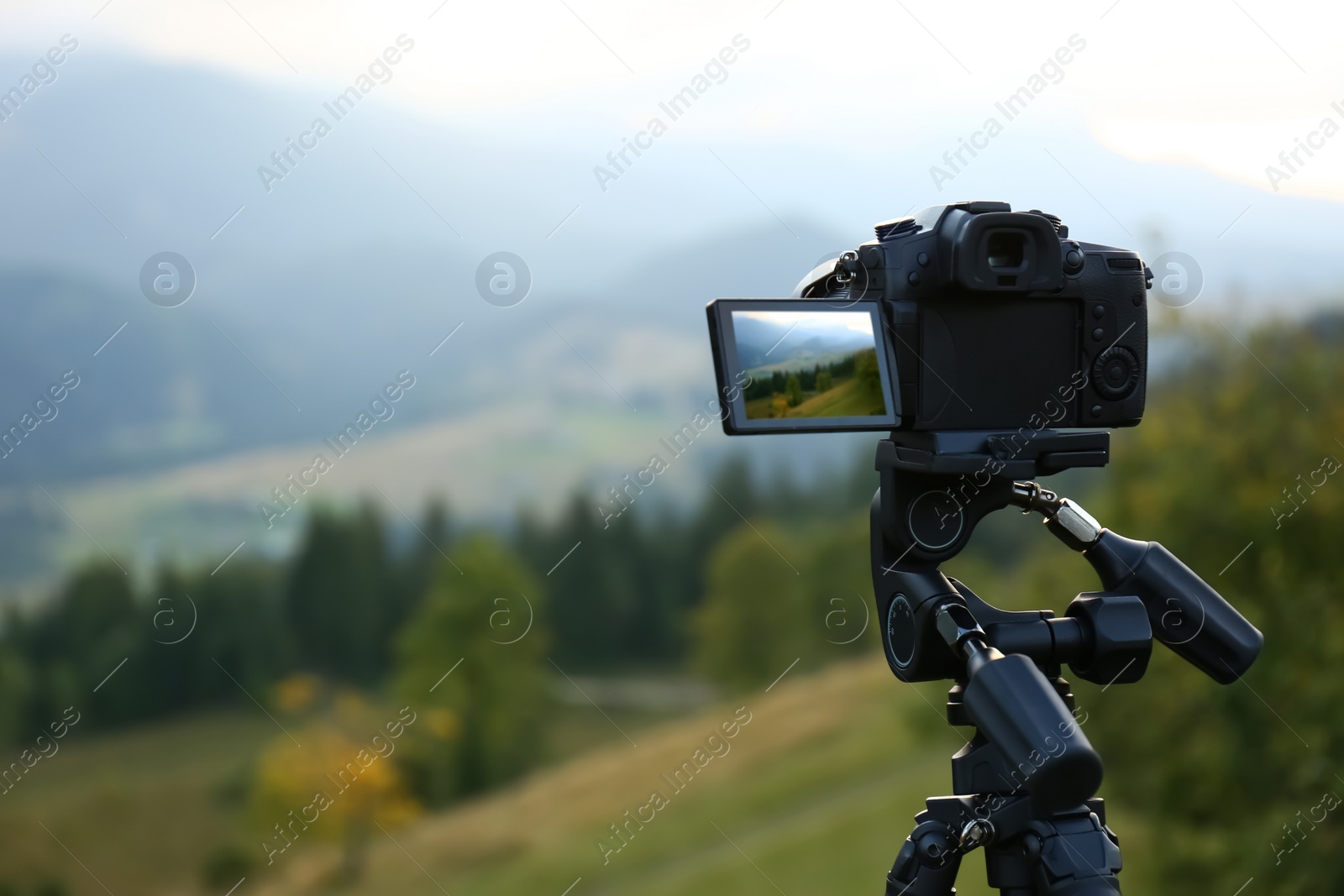 Photo of Taking video with modern camera on tripod in mountains