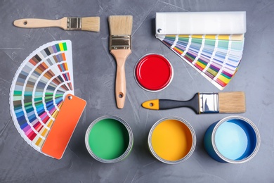 Photo of Flat lay composition with cans of paint, brushes and color palette samples on gray background