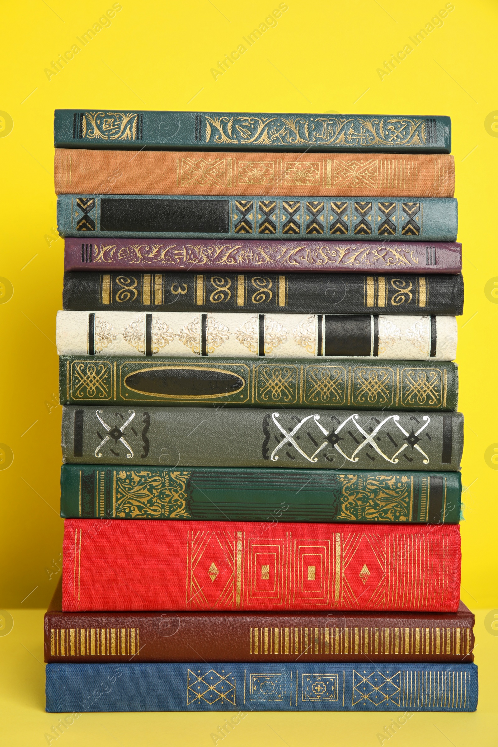Photo of Stack of different hardcover books on yellow background
