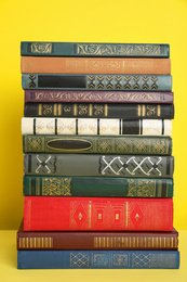 Stack of different hardcover books on yellow background