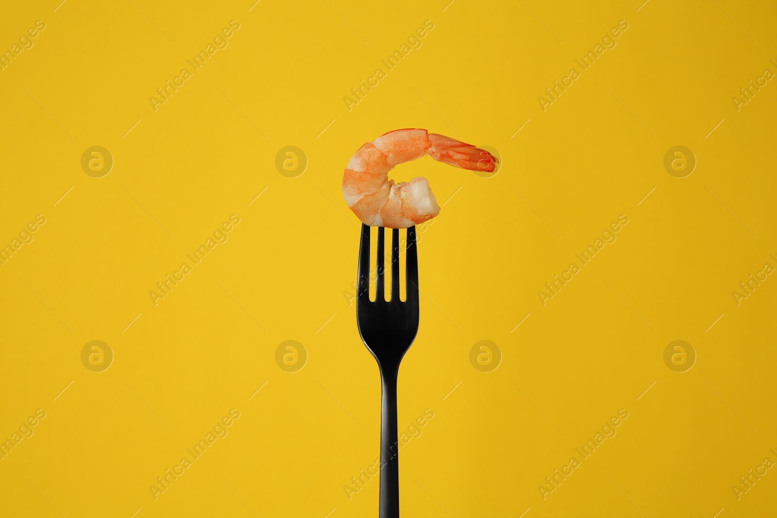 Photo of Fork with one shrimp on yellow background