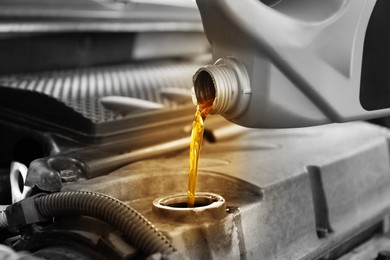 Image of Pouring motor oil into car engine, closeup. Color accent effect