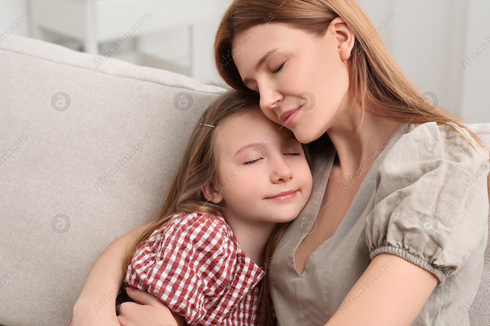 Photo of Mother and her cute daughter on sofa at home