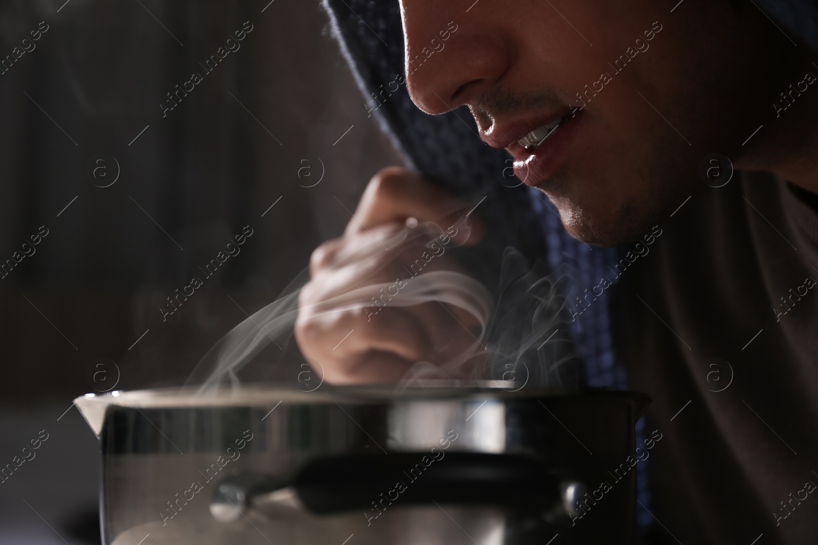 Photo of Man with plaid doing inhalation above saucepot, closeup