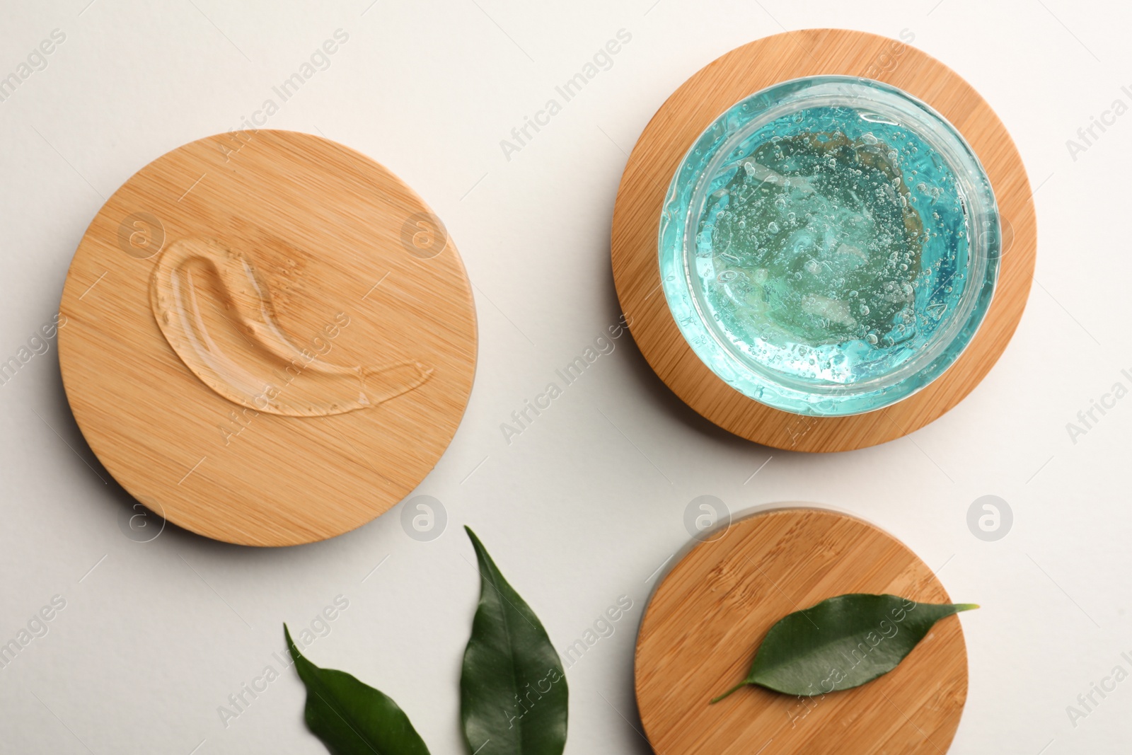 Photo of Flat lay composition with blue cosmetic gel and leaves on white background