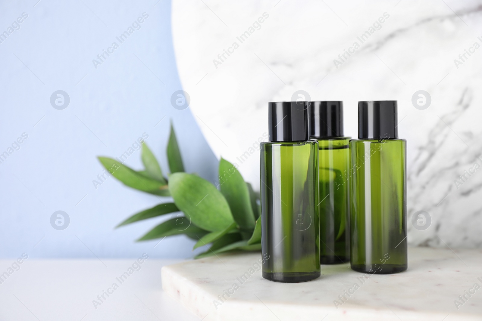 Photo of Mini bottles with cosmetic products on white table. Space for text