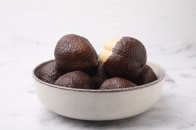 Photo of Fresh salak fruits in bowl on white marble table, closeup