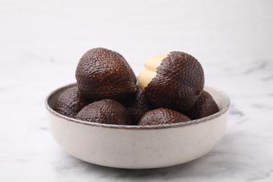 Fresh salak fruits in bowl on white marble table, closeup