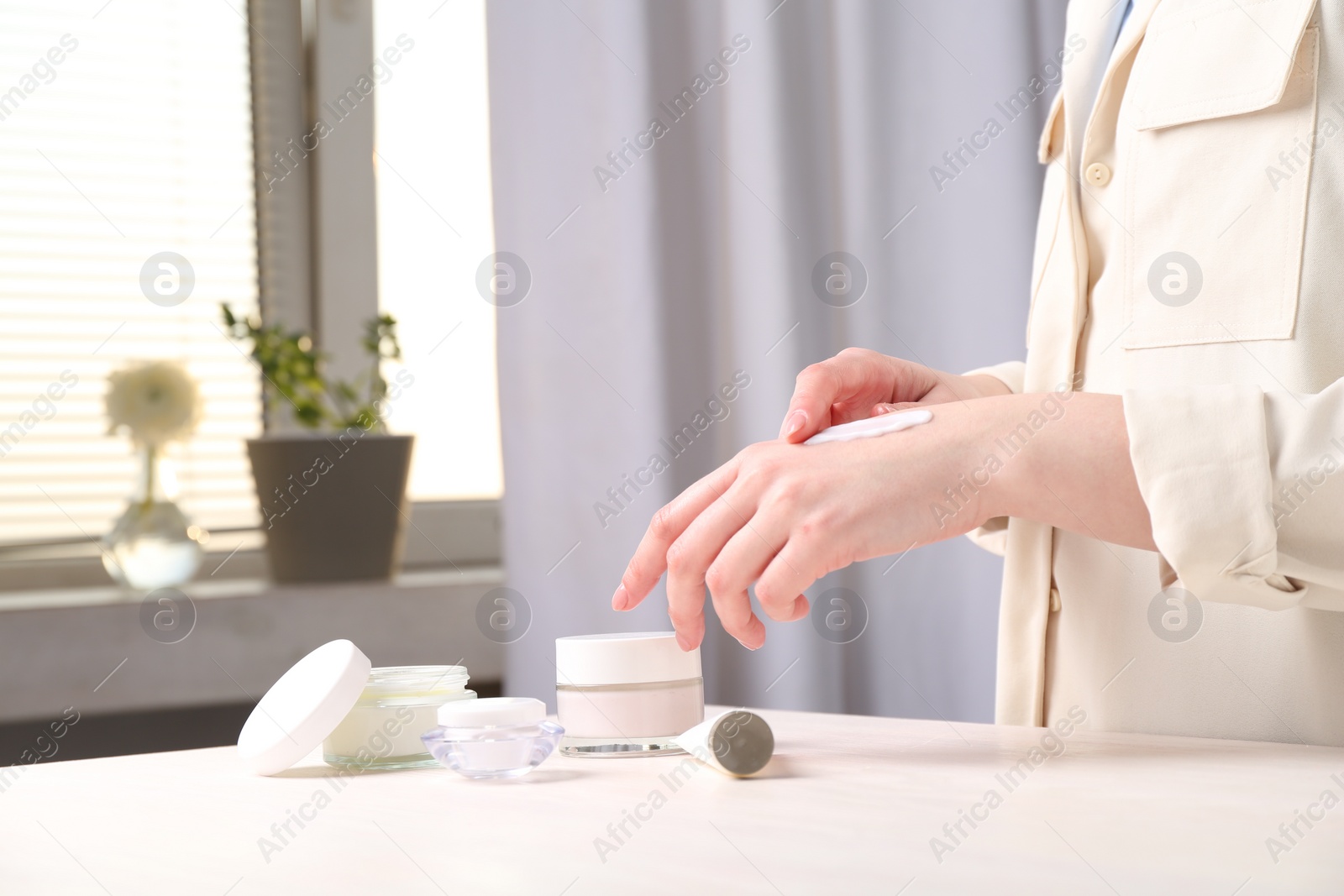 Photo of Woman applying hand cream at home, closeup