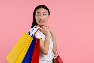 Photo of Smiling woman with shopping bags on pink background. Space for text