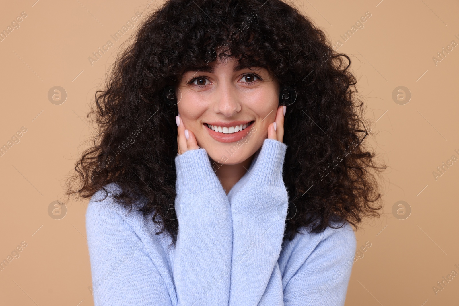 Photo of Happy young woman in stylish light blue sweater on beige background