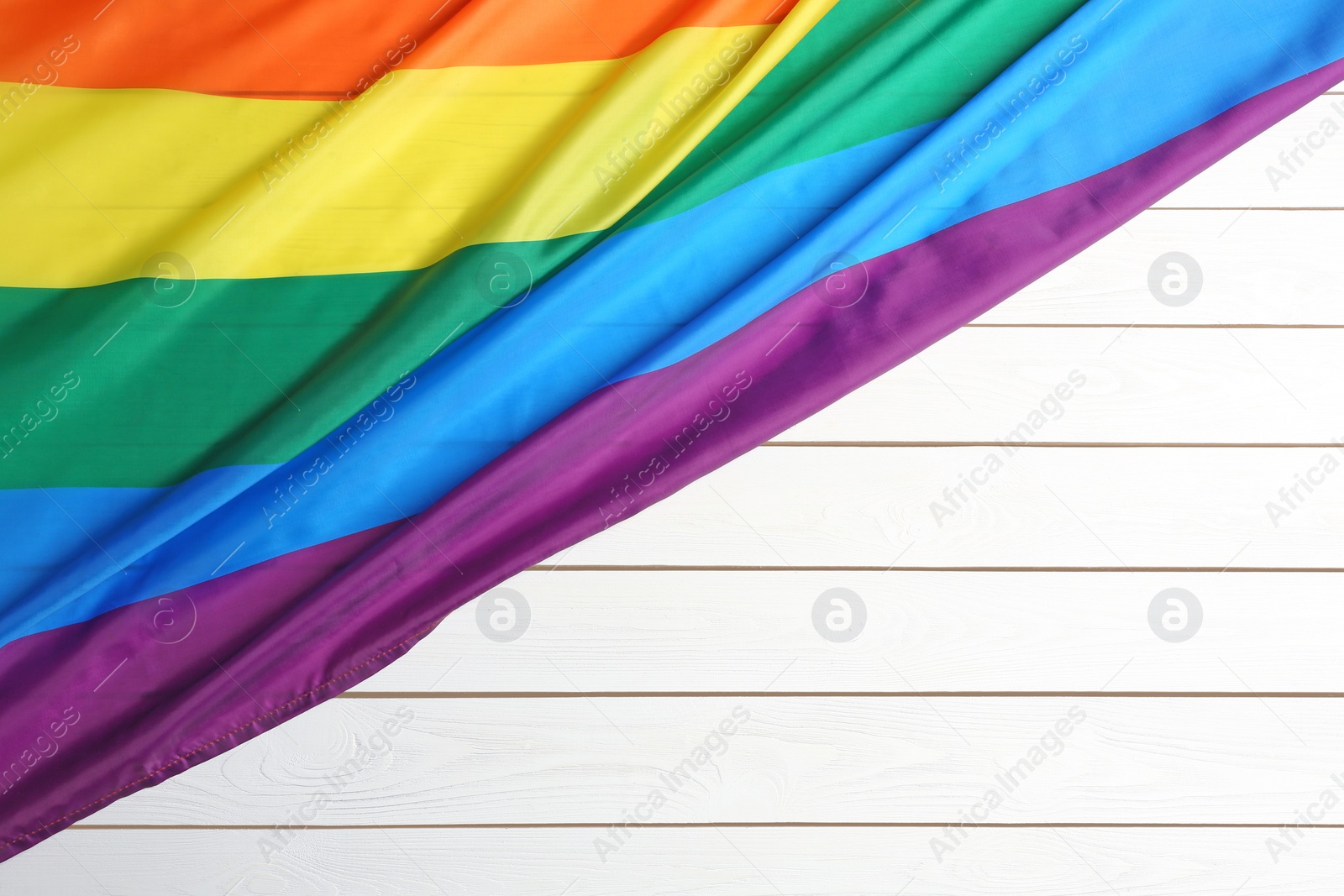 Photo of Bright rainbow gay flag on wooden background, top view with space for text. LGBT community