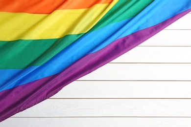 Photo of Bright rainbow gay flag on wooden background, top view with space for text. LGBT community