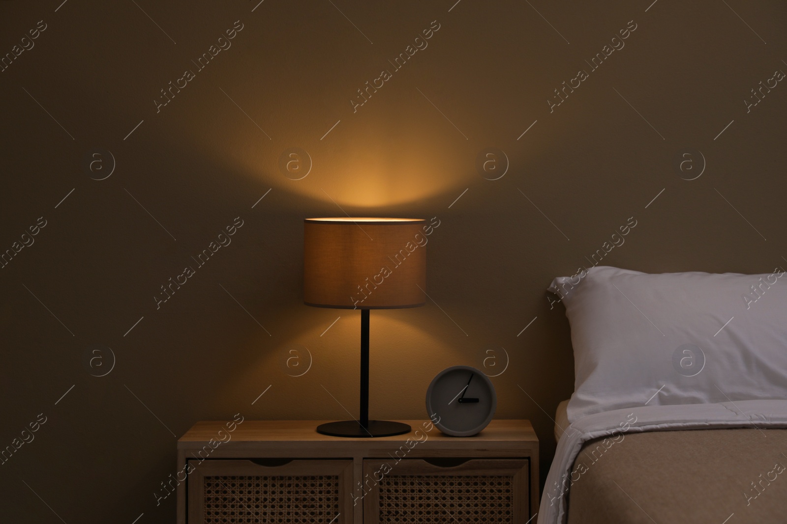 Photo of Stylish night lamp on bedside table in bedroom