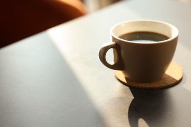 Photo of Cup of delicious coffee on grey table indoors, closeup. Space for text
