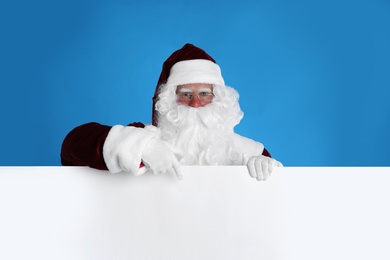 Photo of Santa Claus holding empty banner on light blue background