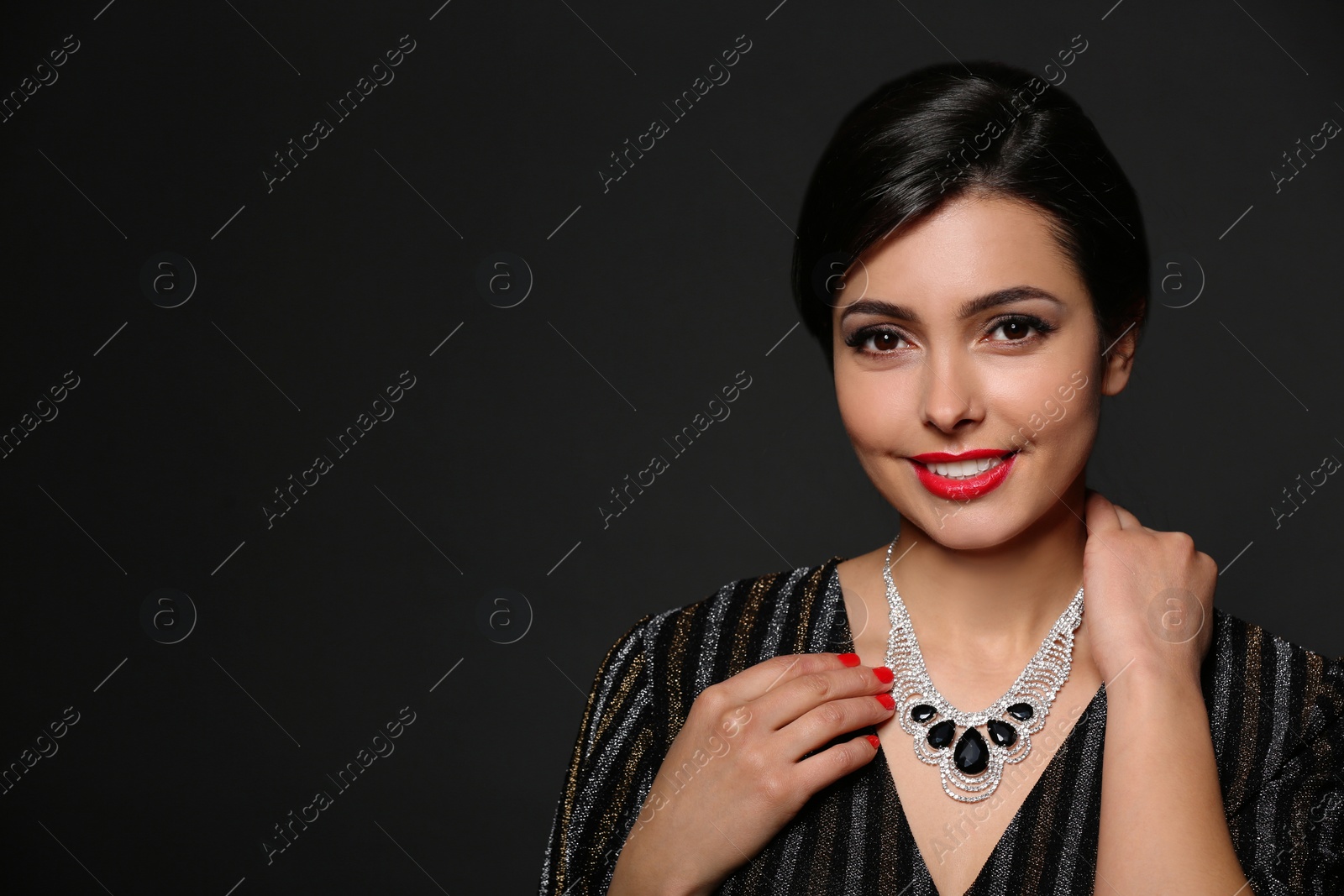 Photo of Beautiful young woman with elegant jewelry on dark background. Space for text