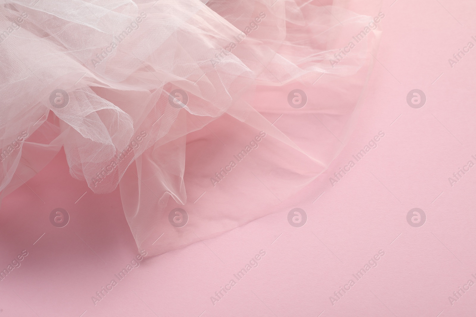 Photo of Beautiful white tulle fabric on pink background
