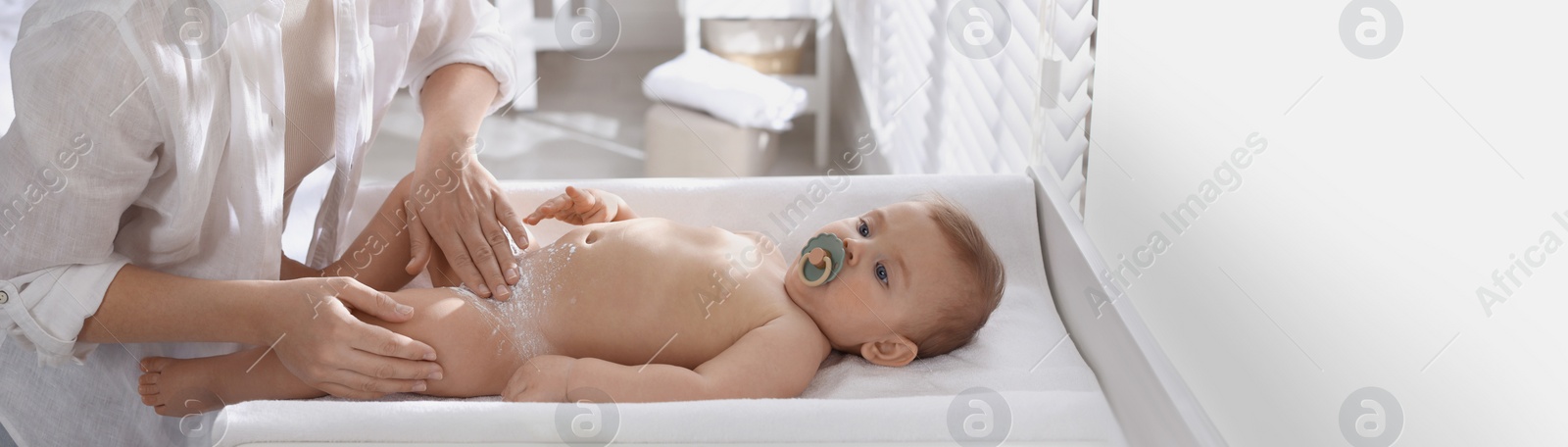 Image of Mother applying dusting powder on her cute baby at home. Banner design