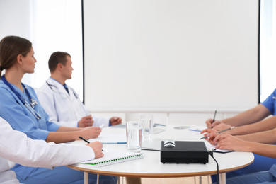 Team of doctors using video projector during conference indoors