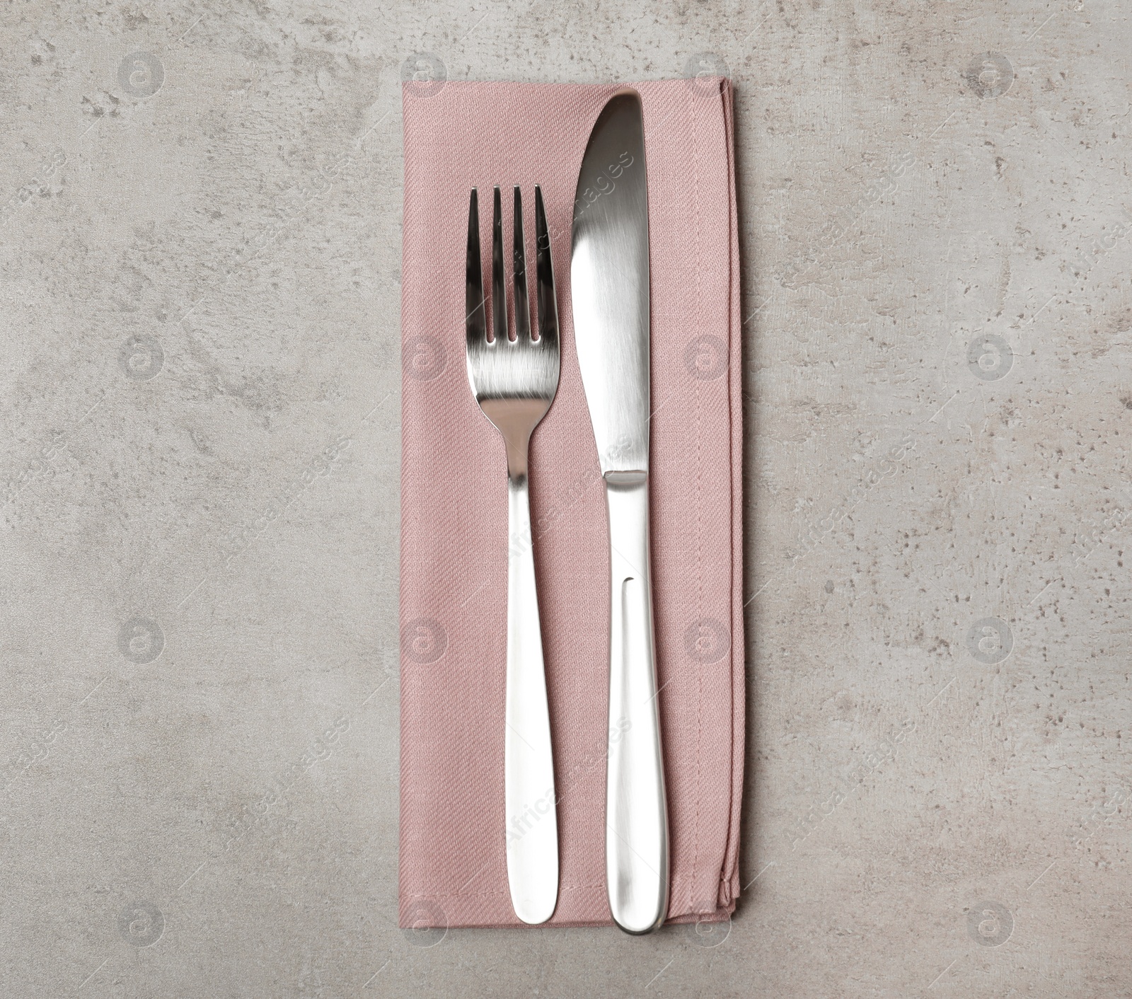 Photo of Fork, knife and linen napkin on grey background, top view