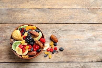 Photo of Bowl of different dried fruits on wooden background, top view with space for text. Healthy lifestyle
