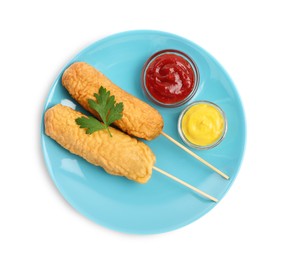 Photo of Delicious deep fried corn dogs with parsley and sauces on white background, top view