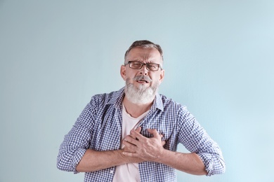 Photo of Mature man having heart attack on color background